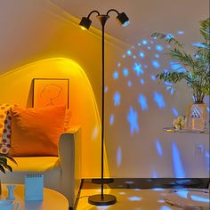 a living room with a white couch and yellow chair in front of a wall that has blue lights on it