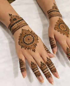 two hands with henna tattoos on them