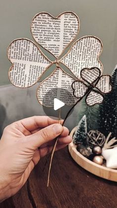 a person holding up a four leaf clover on top of a wooden table next to a christmas tree