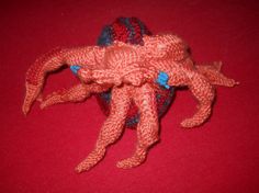 an orange crocheted object sitting on top of a red surface