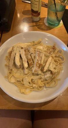 a white plate topped with pasta covered in sauce and chicken breast pieces on top of it