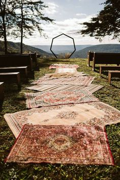 many rugs are laid out on the grass in front of some benches and trees