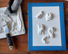 some white icing is sitting on a table next to a blue and white frame