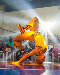 a man doing a handstand on top of a blue and purple floor in front of an audience