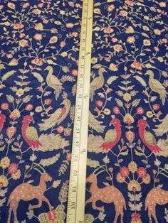 a ruler is next to a blue fabric with flowers and birds on it's side