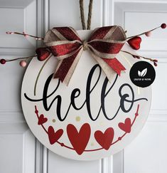 a door hanger with the word hello painted on it and a bow tied to it