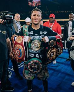 the professional boxer is holding his belts in one hand and smiling at the camera while surrounded by photographers