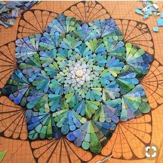 an intricately designed piece of art made out of blue and green glass pieces on a wooden table