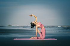 a woman is doing yoga on the beach