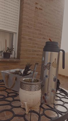 a coffee cup sitting on top of a metal table next to a planter and pot