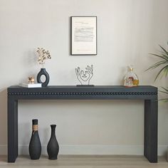 three vases are sitting on a table in front of a wall with a sign