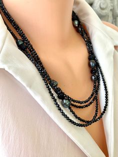 "Luxurious and versatile piece that seamlessly combines the deep black sparkle of spinel with the unique and irregular beauty of black Tahitian baroque pearls.  The length and festive design make it an ideal accessory for special occasions, allowing for various styling options, including layering with other necklaces. Black spinel exhibits a captivating sparkle, adding a touch of glamour and sophistication to the necklace, while Tahitian Baroque pearls add a natural and organic element to it. I added Black rhinestone Polymer clay beads for more sparkles and secured it with a sterling silver lobster clasp. (adding a clasp allows you to wear it as one, two or three strands necklace) MATERIALS: Faceted black Spinel Tahitian baroque pearls, circled surface on some Sterling silver lobster clasp Baroque Pearls Necklace, Necklaces Black, Three Strand Necklace, Black Pearl Necklace, Diy Jewelry Unique, Layering Necklaces, Pearls Necklace, Long Beaded Necklace, Festive Design