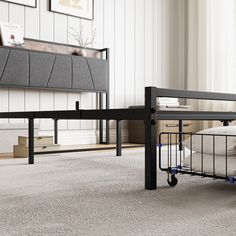 a metal bed frame with wheels is in the middle of an empty room, next to a couch