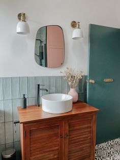 a bathroom with a sink, mirror and wooden cabinet in the corner next to a green door