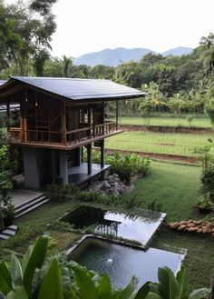 a house in the middle of a lush green field next to a pond and trees