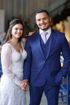 a man in a blue suit and woman in a white dress smile at the camera