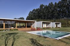 a house with a swimming pool in the middle of a lawn and trees behind it