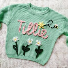 a green sweater with flowers on it and the word tweee written in pink