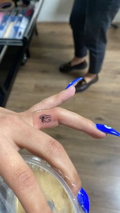 a woman's hand with a small tattoo on her left ring finger, in front of a store display