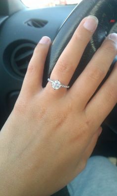 a woman's hand on the steering wheel of a car with a diamond ring