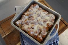 a pan filled with food sitting on top of a wooden table next to a blue towel