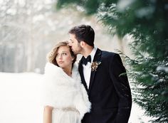 a bride and groom standing in the snow