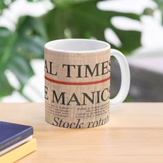 a coffee mug sitting on top of a wooden table next to a stack of books