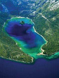 an aerial view of the blue water and green land in the middle of the ocean