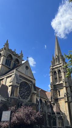 an old church with steeples and trees in the foreground, against a blue sky