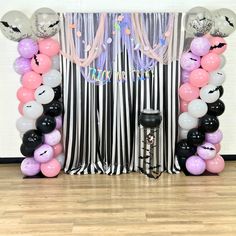 the balloon arch is decorated with black, white and pink balloons