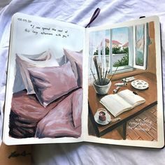 an open book on a bed next to a cup and pen with writing in it