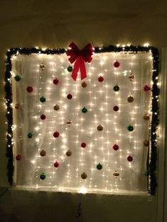 christmas lights and ornaments are hung on the wall in front of a window with a red bow