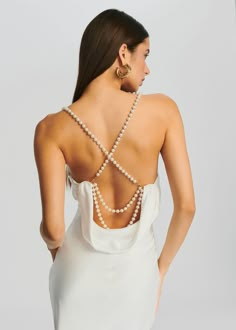 a woman in a white dress with pearls on her back