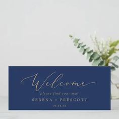 a blue welcome card with the word welcome on it next to a vase filled with flowers