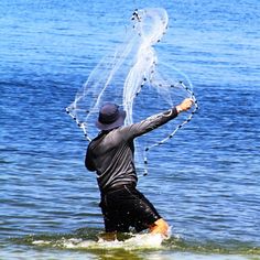 a man wading in the water with a net on his head and arms outstretched