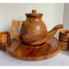 a wooden teapot and four cups on a tray