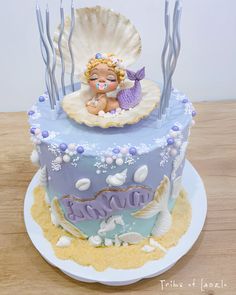 there is a cake decorated with an image of a baby mermaid on the bottom tier