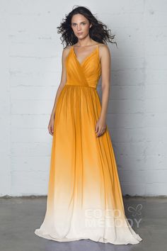 a woman in an orange and white ombreed dress standing against a brick wall