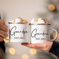 two people holding coffee mugs with marshmallows in them and the words grandpaa est 2022