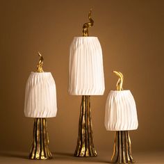 three lamps with white shades and gold details on the top one is shaped like a bird