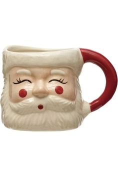 a ceramic mug with a santa claus face on it's side and red handles