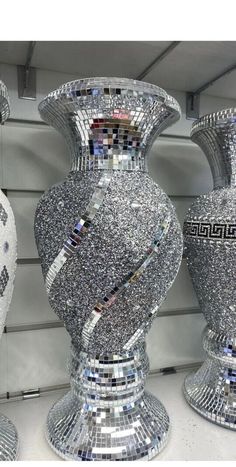 three silver vases are sitting next to each other in front of a white wall