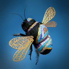 a bee with multicolored wings flying in the air on a blue background,