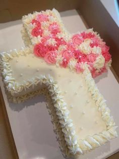 a cake shaped like the letter t with pink and white frosting flowers on it