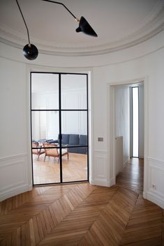 an empty room with wooden flooring and large glass doors leading to the living room