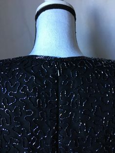 "Ooh la la-so fancy! The beads are spectacular and the scalloped hem and sleeves are pretty cool, too. Shiny black evening wear, somewhat Erica Kane or Alexis Carrington. Elegant and not to be trifled with. Description: Brilliante by J.A. Size S (please see measurements) black with black beading short sleeves shoulder pads back zipper 100% silk do not dry clean/spot clean only Vintage: 1980s Condition: very good few missing beads near zipper (I do have most of them that I will include) please se Formal Black Embellished Blouse, Vintage Embellished Evening Blouse, Vintage Beaded Evening Tops, Vintage Black Enamel Necklace For Evening, Alexis Carrington, Elastic Waistband Skirt, Pointy Collar, Black Embellished Sequin Fabric, Glamorous Style, Asymmetrical Shirt