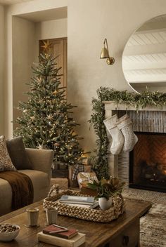 a living room filled with furniture and a christmas tree in front of a fire place