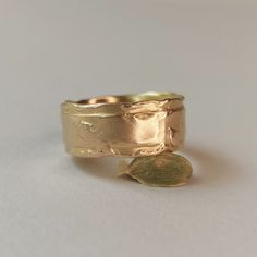 a close up of a gold ring on a white surface with a leaf in the middle