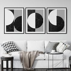 two black and white paintings hang on the wall above a couch in a living room