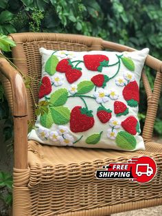 a pillow with strawberries on it sitting on a wicker chair